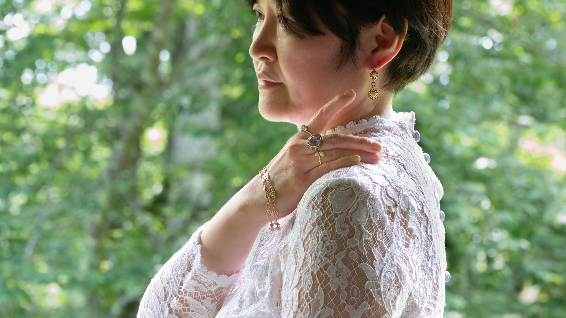 フィリグリーブレスレット、ダイヤのリング、パールのドルムーズピアスなどのアンティークジュエリーを身に付けた女性