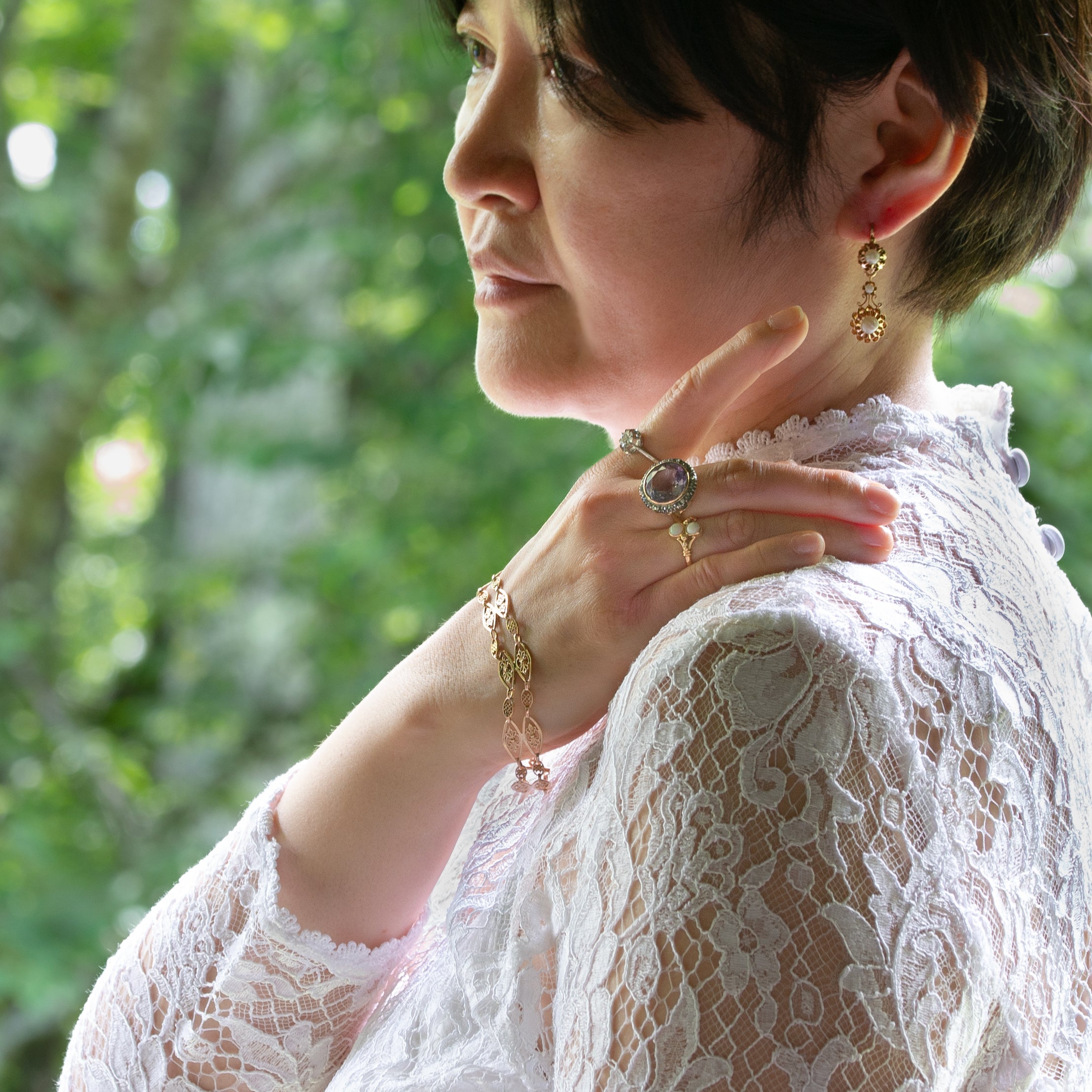 フィリグリーブレスレット、ダイヤのリング、パールのドルムーズピアスなどのアンティークジュエリーを身に付けた女性